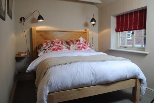a bedroom with a bed with a wooden headboard and a window at Courtyard Cottages Lymington, 2 Adults only in Lymington