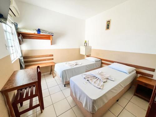 a room with two beds and a table at Hotel Laura Vicunha in Corumbá