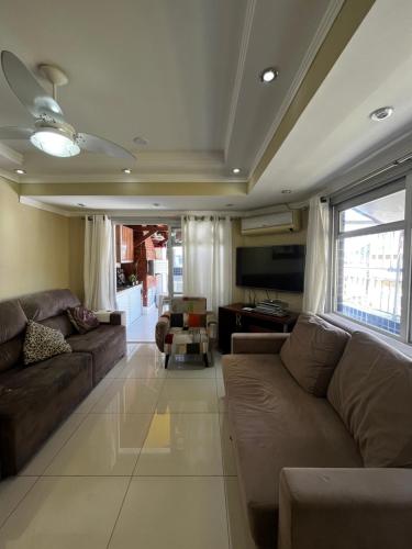 Una sala de estar con un sofá y un televisor. en Cobertura com Piscina e Churrasqueira Privativa, en Guarujá