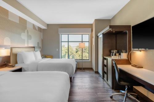 a hotel room with two beds and a desk at Cambria Hotel College Park in College Park