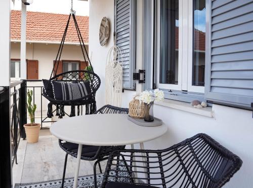 un patio con tavolo e sedie bianchi sul balcone. di Lefkada City Escape a Città di Lefkada