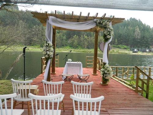 a gazebo with chairs and a table on a dock at Cabañas rio chovellen in Curanipe