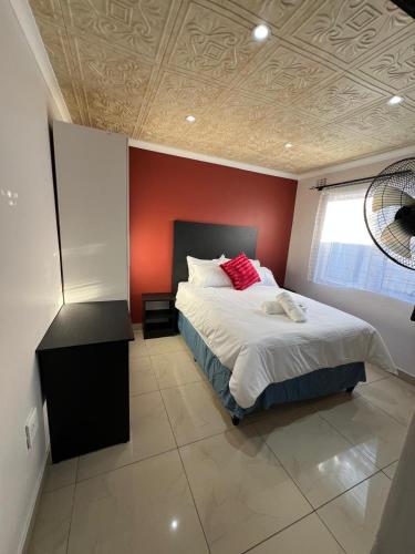 a bedroom with a bed with a red wall at Our Home Guest House in Bellville
