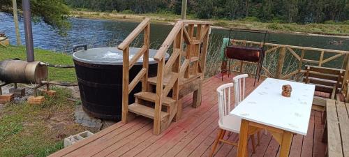 a wooden deck with a hot tub and a table and stairs at Cabañas rio chovellen in Curanipe