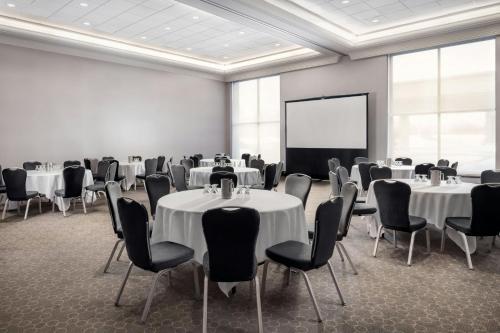 a conference room with tables and chairs and a screen at Sheraton Toronto Airport Hotel & Conference Centre in Toronto