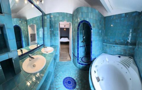 La salle de bains est pourvue de carrelage bleu, d'une baignoire et d'un lavabo. dans l'établissement Résidence Bastide - Magnifique maison a 200m de la mer avec piscine privée spa et terrain de pétanque MAE-5901, à Six-Fours-les-Plages