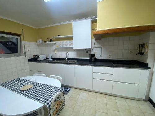 eine Küche mit weißen Schränken und einem Tisch und einer Spüle in der Unterkunft A Terraza da Filipa in Vila Praia de Âncora