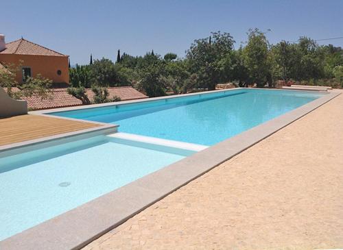 a large blue swimming pool in front of a house at Quinta Rosa Amarela in Boliqueime