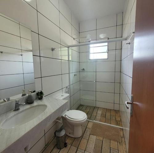 a white bathroom with a toilet and a sink at Flor do Campo in Serra do Cipo