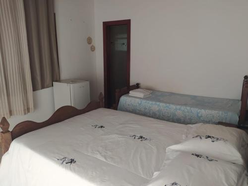 a bedroom with two beds with white sheets at Pousada da Elizângela de Amarantina in Ouro Preto