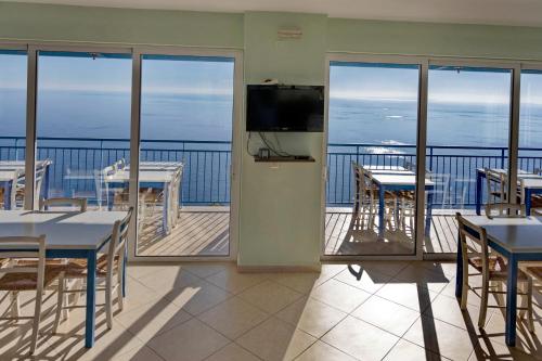 a dining room with tables and chairs on a balcony at Akrotiri Panorama- luxury rental apartments with sea view in Rodakino