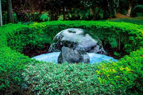 a statue of a water fountain in the grass at Good News Hotel in Kigali