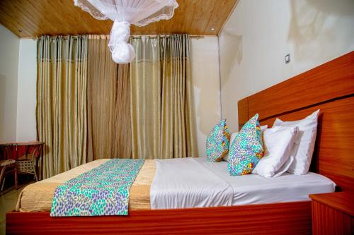 a bedroom with a bed with a wooden headboard and pillows at Good News Hotel in Kigali