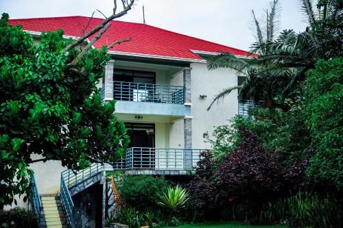 a white house with a red roof and trees at Good News Hotel in Kigali