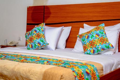 a bed with three pillows on top of it at Good News Hotel in Kigali