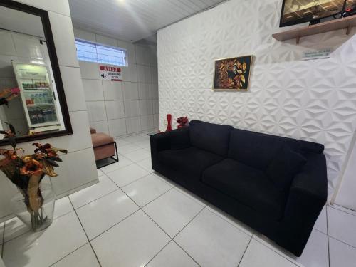 a living room with a black couch in a room at Casa Aeroporto Pousada in Recife