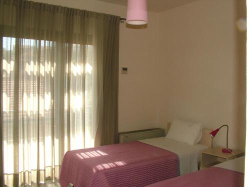 a bedroom with two beds and a large window at Sugar and Almond in Agios Stefanos