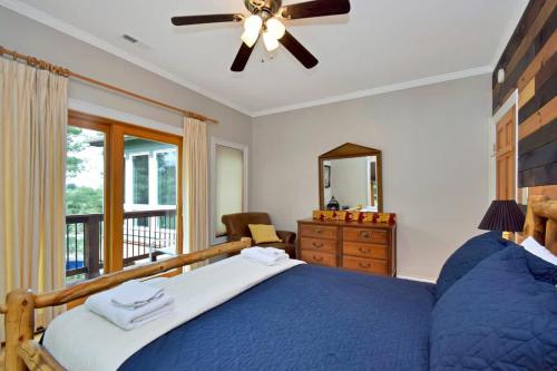 a bedroom with a blue bed with a ceiling fan at Boone Mountain Getaway- Hot Tub Firepit in Boone