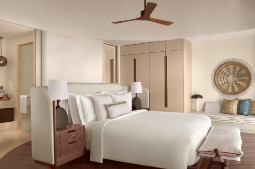 a white bedroom with a white bed and a ceiling fan at Nujuma, a Ritz-Carlton Reserve in Ḩanak