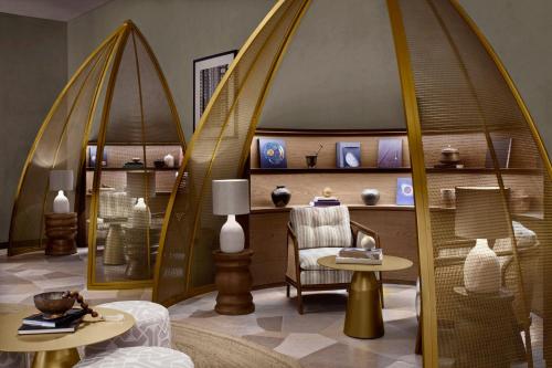 a room with a chair and tables and shelves with vases at Nujuma, a Ritz-Carlton Reserve in Ḩanak