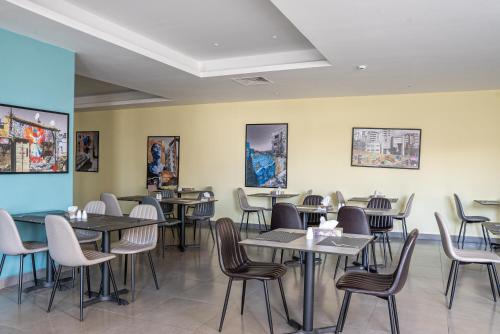 a dining room with tables and chairs and paintings at Liv Weibdeh Hotel Suites in Amman