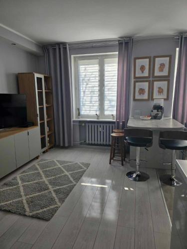 Una sala de estar con televisión, mesa y sillas. en Bee Happy Apartament Wrzesnia, en Września