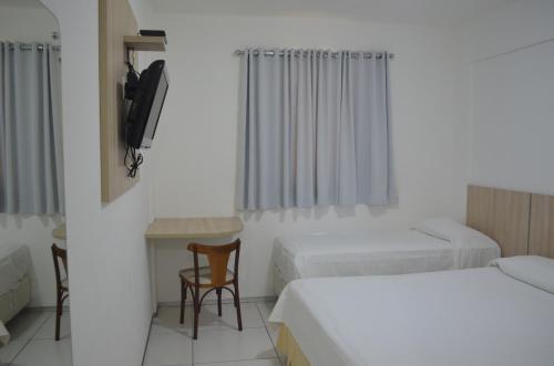 a room with two beds and a table and chairs at Annamar Hotel in João Pessoa