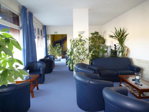 a waiting room with blue chairs and tables and plants at Le Relais de la route bleue in Saint-Loup