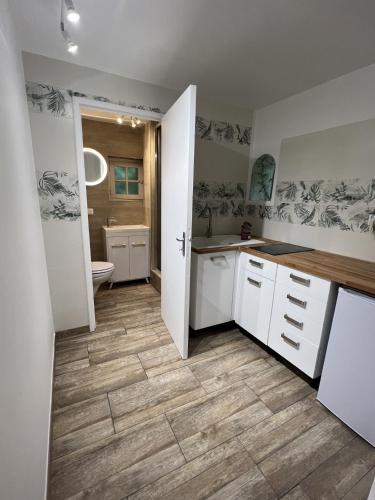 une cuisine avec des armoires blanches et un plancher en bois dans l'établissement Gîte 1 Château Bellenau, à Saint-Côme-du-Mont