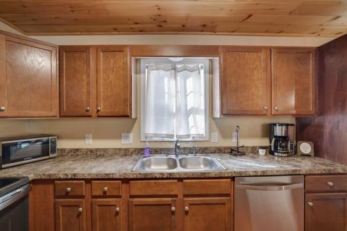 a kitchen with wooden cabinets and a sink and a window at Modern 6BR Cabin- Hot Tub Theater Basketball in White Haven