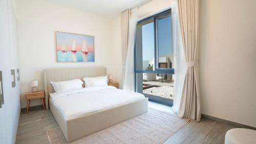 a white bedroom with a bed and a large window at 4br Spacious Villa Backyard in Abu Dhabi