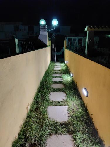 a pathway with grass on the side of a wall at night at Enjoy The Sea in Calasetta