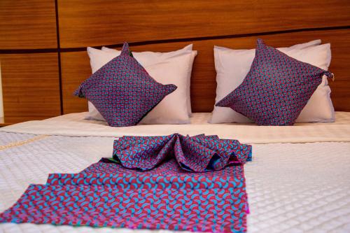 a bed with blue and red pillows on it at Good News Hotel in Kigali