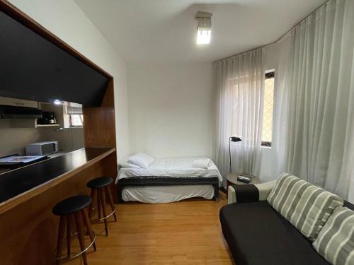 een kamer met een bed, een bank en een keuken bij Apart Hotel Guignard 305 - Moderno e Acolhedor in Belo Horizonte
