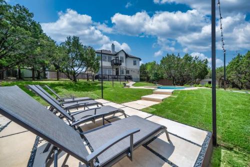 a group of lounge chairs in a yard with a house at Austin Spacious Haven - Pool Jacuzzi Firepit in Bee Cave
