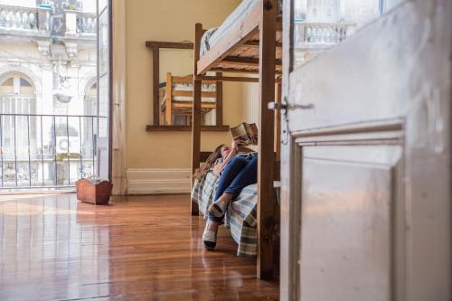 a woman sitting on a bunk bed reading a book at BA Stop Hotel House in Buenos Aires