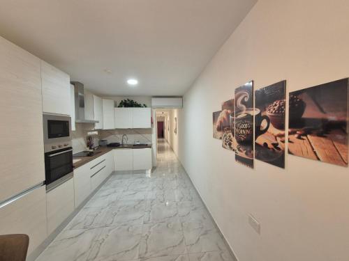 a kitchen with white cabinets and posters on the wall at 3BR Family Stay Near Valletta in Hamrun