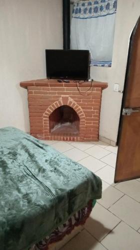 a brick fireplace with a television on top of it at LA HUERTA Cabaña y Hospedaje in Huasca de Ocampo