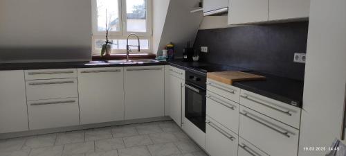 a kitchen with white cabinets and black counter tops at Gemütliche 3 Zimmer Wohnung in Gottmadingen