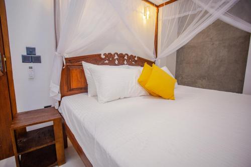 a bedroom with a white bed with a yellow pillow at SHD Paddy Villa in Talpe
