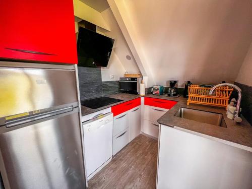 a kitchen with red cabinets and a stainless steel refrigerator at Chalet baie de La Forêt-Fouesnant in La Forêt-Fouesnant