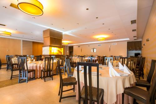 Grand Hotel Napoca في كلوي نابوكا: غرفة طعام مع طاولات وكراسي ومدفأة