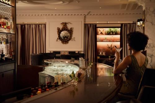 a woman standing at a bar with a drink at InterContinental New York Barclay Hotel by IHG in New York