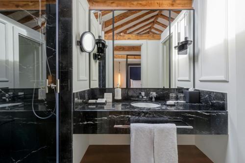 a black bathroom with a sink and a mirror at El Autor Hotel, Madrid, Autograph Collection in Madrid