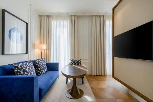 a living room with a blue couch and a table at El Autor Hotel, Madrid, Autograph Collection in Madrid