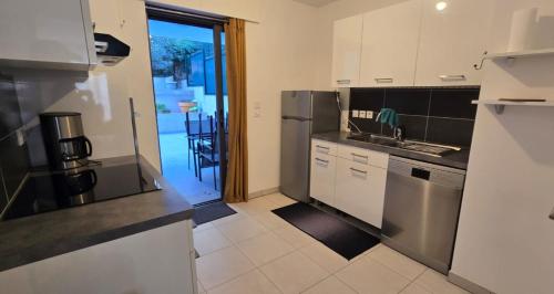 une cuisine avec des appareils en acier inoxydable et une porte donnant sur une terrasse. dans l'établissement Spacious T3 with garden in Saint-Raphaël, à Saint-Raphaël