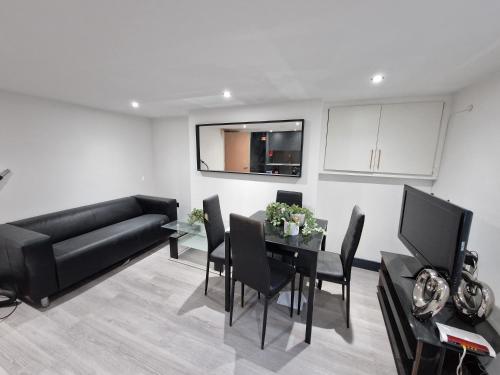 a living room with a black couch and a table at Stylish 3 bed 3 ensuites house with parking & garden in Reading
