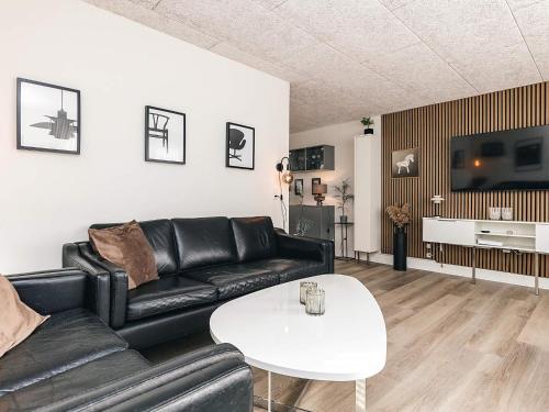 a living room with a black leather couch and a white table at 8 person holiday home in Bagenkop-By Traum in Bagenkop