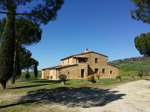 an old stone building in a field with trees at Agriturismo Il Casalino in Pienza