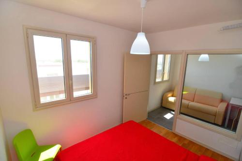a bedroom with a red bed and a chair and window at Boomerang Village in Torre Colimena